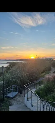 a sunset on a beach with a stairway leading to the ocean at АМИРА апартамент за гости - AMIRA guest apartment in Burgas City