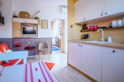 a kitchen with white cabinets and a sink and a table at Villa Mare Boutique Guesthouse by Flat Mаnаger in Pomorie