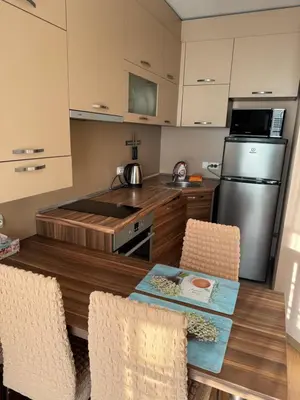 a kitchen with a table and chairs and a refrigerator at Апартамент с одной спальней in Sunny Beach