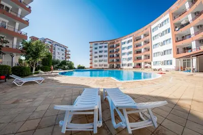 two chairs and a swimming pool in a building at Riviera Fort Beach Apartment in Ravda