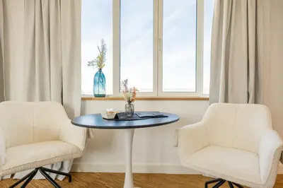 two chairs and a table in a room with two windows at Apartment Musala N 03 in Varna City