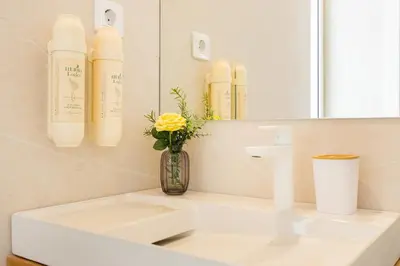 a bathroom with a sink and a vase with a yellow flower at Apartment Musala N 04 in Varna City