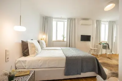 a white bedroom with a bed and a dining room at Apartment Musala N 04 in Varna City