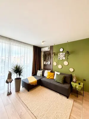 a living room with a couch and a green wall at Orchid Fort Noks Design in Sunny Beach