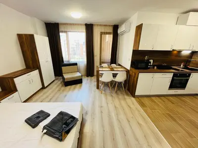 a room with a bed and a kitchen with a table at Апартаменти Тутхон Поморие in Pomorie