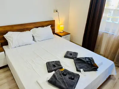 a bedroom with a white bed with towels on it at Апартаменти Тутхон Поморие in Pomorie