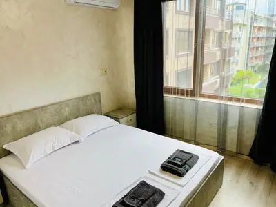 a bed in a room with a large window at Апартаменти Тутхон Поморие in Pomorie