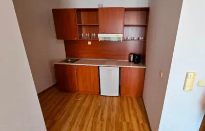 a small kitchen with wooden cabinets and a white refrigerator at Апартамент Del View гр Приморско in Primorsko
