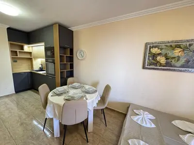 a dining room with a table and a kitchen at Private Apartments Olymp in Sveti Vlas