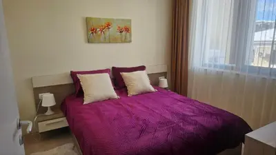 a bedroom with a purple bed with a window at Vladan apartments in Sozopol