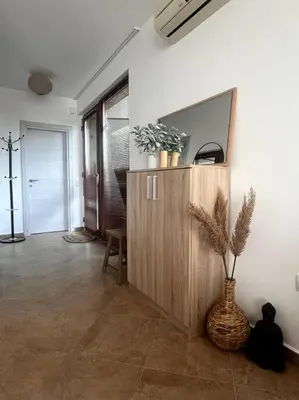 a living room with a cabinet and a vase with a plant at Panorama Bay-Serenity Haven in Burgas City