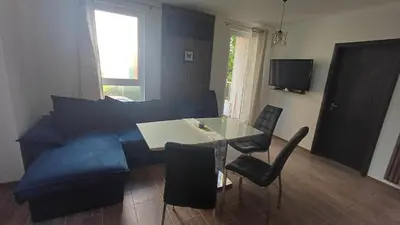 a living room with a blue couch and a table and chairs at Синя пеперуда Blue butterfly in Primorsko