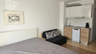 a bedroom with a bed and a chair and a kitchen at Vladan apartments in Sozopol