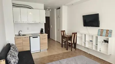 a kitchen with white cabinets and a sink and a table at Vladan apartments in Sozopol