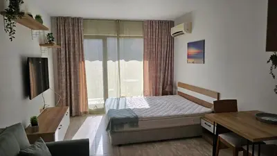 a bedroom with a bed and a desk and a window at Vladan apartments in Sozopol
