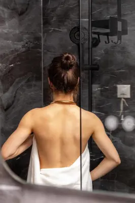 a woman in a shower looking at her back at Noma Boutique Hotel - Adults only in Sunny Beach