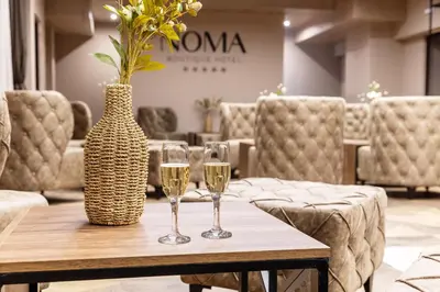 two glasses of wine on a wooden table with a vase at Noma Boutique Hotel - Adults only in Sunny Beach