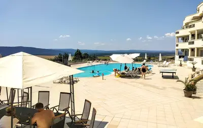 a group of people sitting around a swimming pool at SunBreeze Living Apartments in Byala