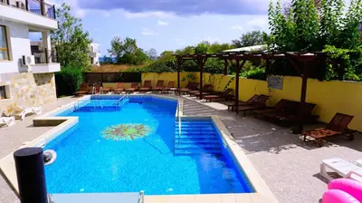 a large blue swimming pool with chairs and an umbrella at Бяла Виста Бийч Апартментс A - Byala Vista Beach Apartments A in Byala