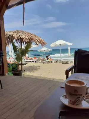a cup of coffee sitting on a table on the beach at Sunshine Byala in Byala