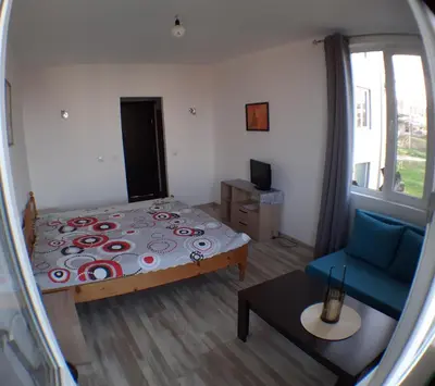 a small bedroom with a bed and a blue chair at Sunshine in Byala
