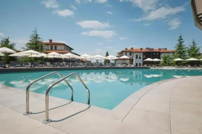 a swimming pool at a resort with chairs and umbrellas at Marina Trio in Sozopol