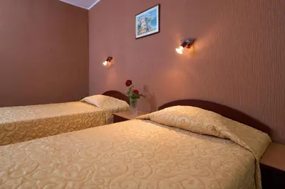 a hotel room with two beds and a vase of flowers at Hotel Smolyan in Sunny Beach