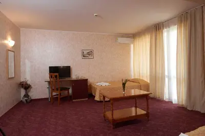 a hotel room with a table and a desk and a television at Hotel Smolyan in Sunny Beach