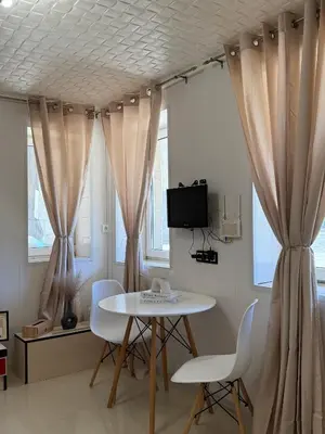 a table and chairs in a room with curtains at Dayanas Suite in Varna City