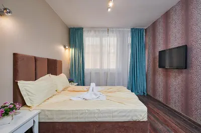 a bedroom with a bed with a tv on a wall at Luxury Apartment Saint George Beauty and Style in Sveti Vlas
