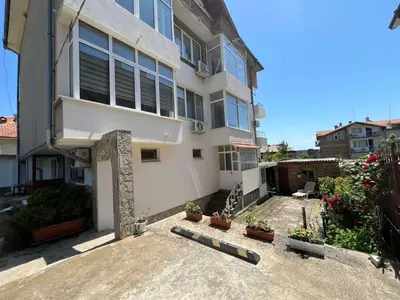 a large white building with potted plants in a courtyard at Luxury Apartment Saint George Beauty and Style in Sveti Vlas