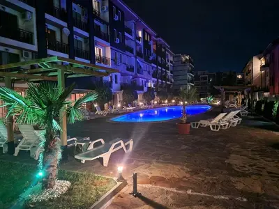 a swimming pool with chairs and a building at night at MitProt Panorama Bay 2 luks Studio 143 in Sveti Vlas