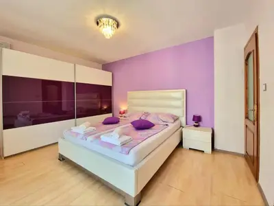 a bedroom with a large bed with purple walls at Sunny View Apartment with Garage in Burgas City