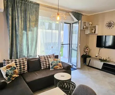 a living room with a couch and a large window at Sunny Garden Deluxe in Burgas City