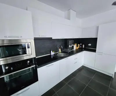 a white kitchen with a sink and a microwave at Rose Garden Deluxe in Chernomorets