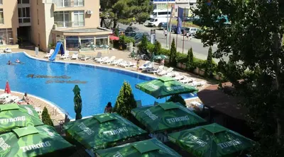 a swimming pool with green umbrellas and chairs and people at Reina Apart Kamelia Garden in Sunny Beach