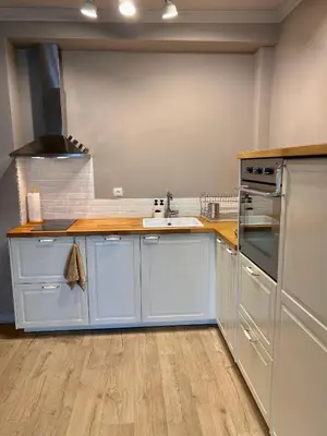 a kitchen with white cabinets and a wooden counter top at Sea Breeze l 2BD Sea Garden Apartment in Varna City