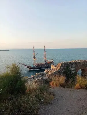 a boat sitting in the water next to the ocean at Sozopol Sunrise in Sozopol