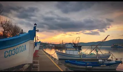 two boats are docked at a dock with a sunset at Sozopol Sunrise in Sozopol