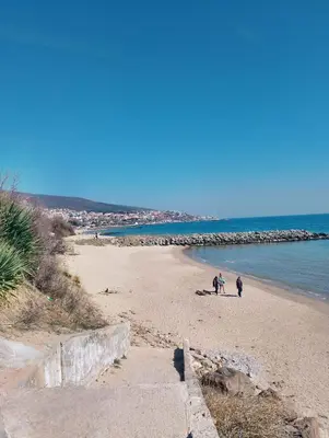 two people walking on a beach near the water at Studio in Sea Breeze Complex Sveti Vlas in Sveti Vlas