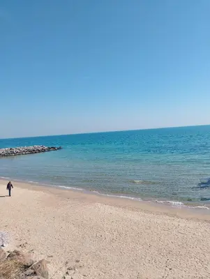 a person walking on a beach near the ocean at Studio in Sea Breeze Complex Sveti Vlas in Sveti Vlas