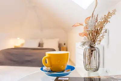 a yellow coffee cup on a glass table with a vase at Apartment Musala N 06 in Varna City
