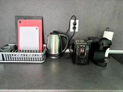 a counter top with a coffee maker a tea pot and a phone at Sea Sunrise Apartment in Burgas City