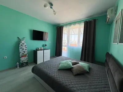 a bedroom with a bed with green walls and a window at Sea Sunrise Apartment in Burgas City