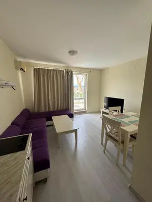 a living room with a purple couch and a table at Sunny Beach Center Apartment in Sunny Beach