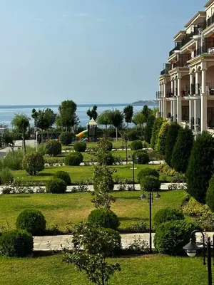 a park with trees and bushes in front of a building at Premier Fort Beach Hotel in Sveti Vlas