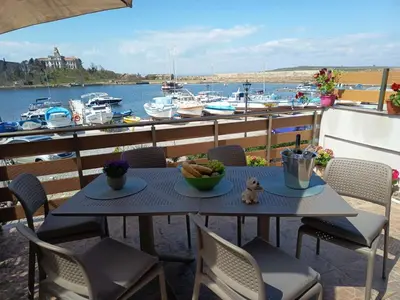 a table and chairs on a balcony with boats in the water at Cozi 2BD Apartment with Sea View in the Old Town of Sozopol in Sozopol