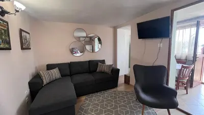 a living room with a black couch and a chair at Cozi 2BD Apartment with Sea View in the Old Town of Sozopol in Sozopol