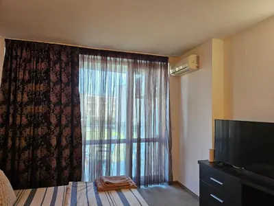 a bedroom with a large window with a television at Студио за нощувки в Сарафово in Burgas City
