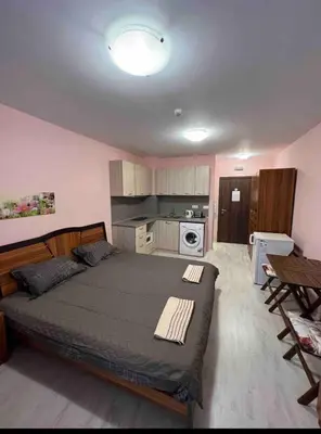 a bedroom with a large bed and a kitchen at Студия в Болгарии Солнечный берег in Sunny Beach